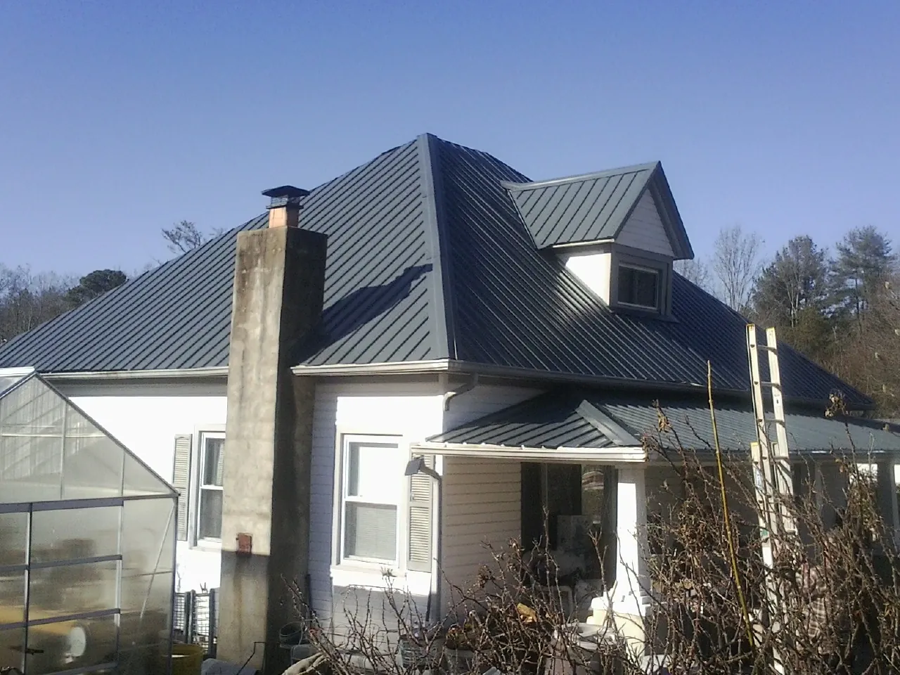 Dark blue standing seam metal roof on a white farmhouse with dormer — Slate & Tile Roof Repair by Roofing Brothers in Westford