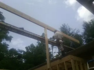 Carpenter setting a ridge beam over a new addition frame — Ice Dam Removal by Roofing Brothers in Westford