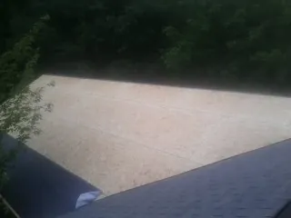 New OSB roof sheathing installed beside an existing shingle roof in Westford