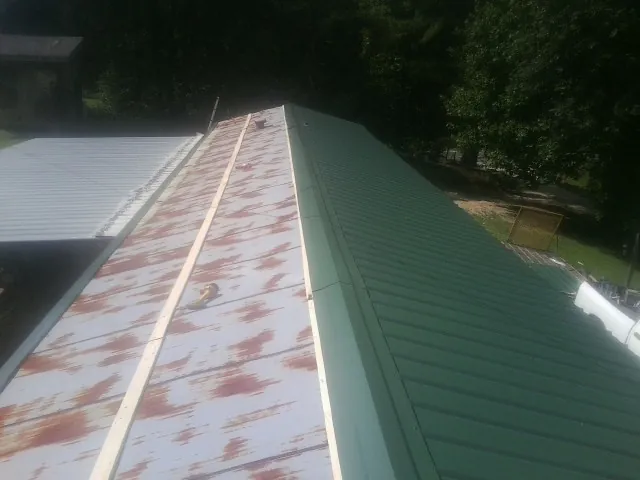 Old rusted panels beside newly installed green metal roofing — Wind Damage Roof Repair by Roofing Brothers in Westford