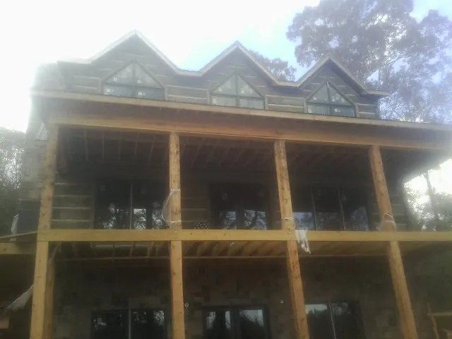Dormers and porch framing on a large log home under construction — Roof Coating work by our crew in Westford