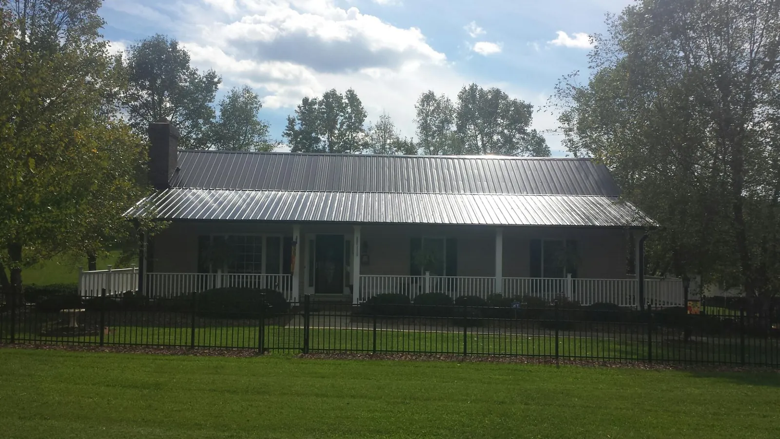 Gray metal roof on a brick ranch with a full width front porch — Gutter Guard Installation work by our crew in Westford