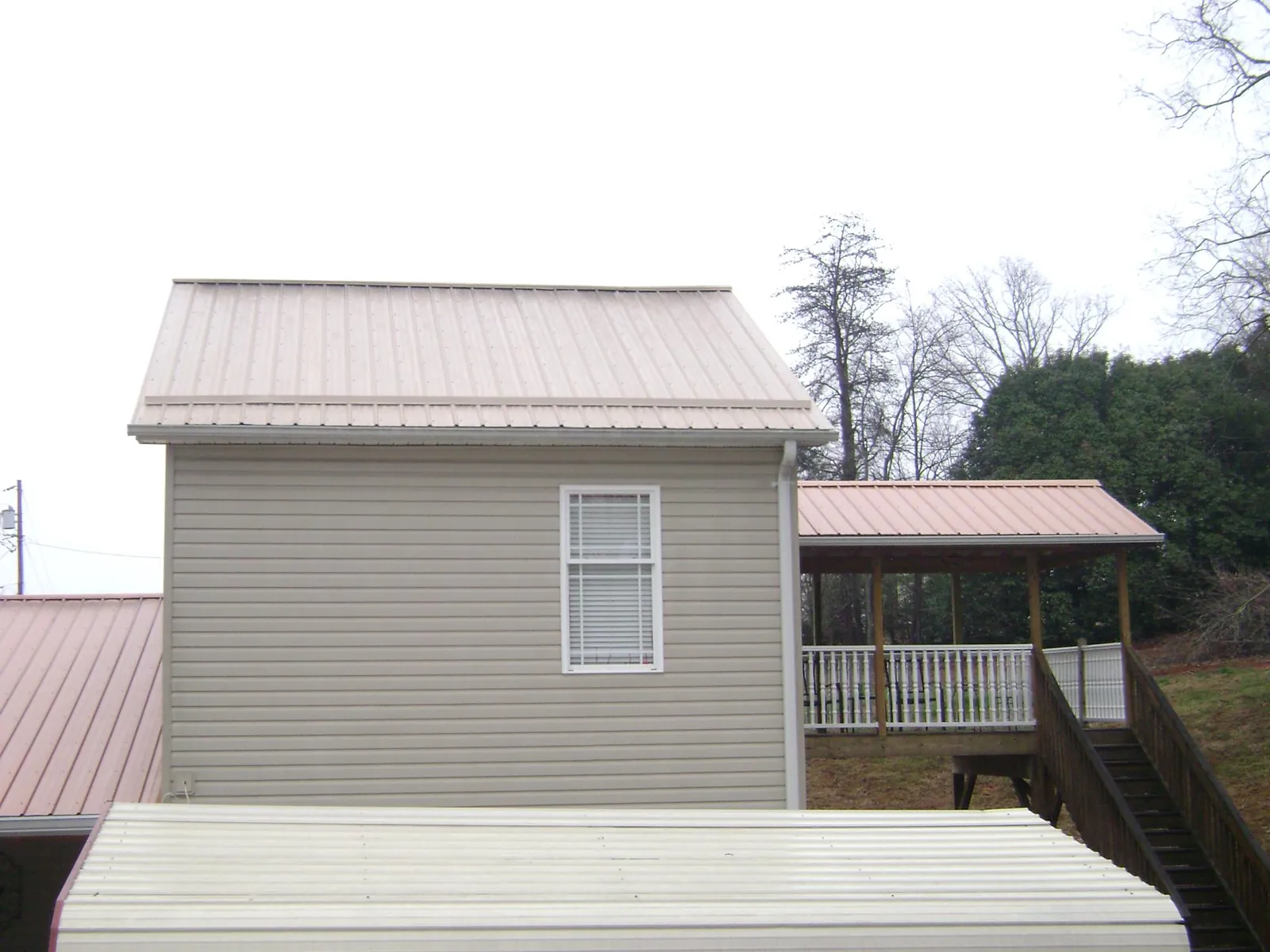 Tan metal roofs on a two story addition and attached porch, from a Roof Replacement job in Westford